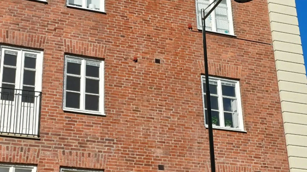 Tegelfasad efter fasadrengöring där märken efter nedtagen skylt har minskat.